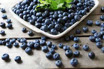 Tasty ripe blueberries with mint on wooden table close up