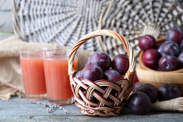 Delicious plum juice with fruits on wicker background