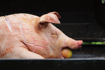 uncooked pig lying on a grill with an apple in the mouth