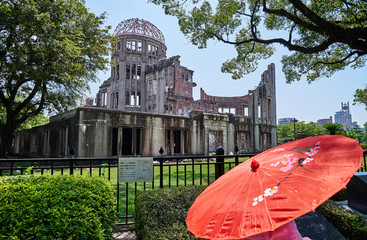 A lady with red umbrella in front of The Dome in Hiroshima
