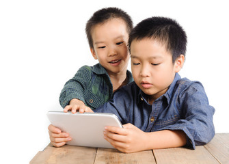 Two Boy sharing tablet device on wood table look happy