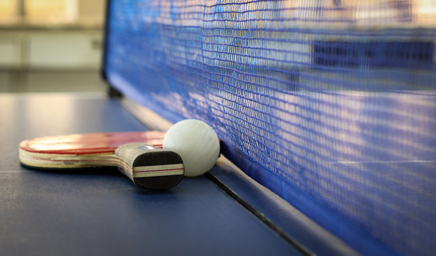 Ping-pong rackets and ball, ping pong tables blue. As in sports and exercise.