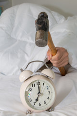 Closeup of a man with a hammer smashing alarm clock