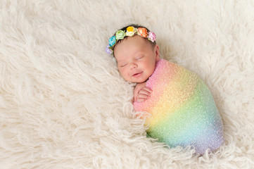 Smiling Newborn Baby Girl Wearing a Rainbow Colored Swaddle