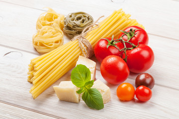 Pasta, tomatoes, basil on wooden table
