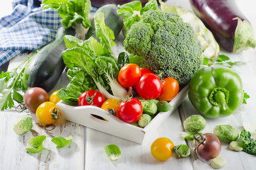 Fresh green organic vegetables on white wooden table.