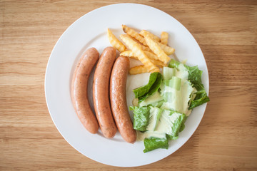 Three pieces of sausage with fresh vegetables, fried potatoes se