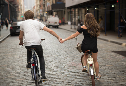 Lovers riding bicycle together holding hands