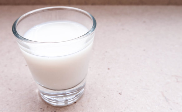Glass of milk standing on brown floor