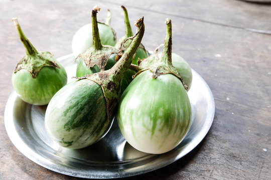 Round Green eggplants on dish on vintage wooden table