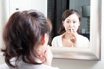 Obraz na płótnie Canvas 鏡を見て化粧をしている日本人女性