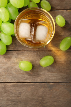 Glass of grape juice with ice cubes on wooden table, closeup
