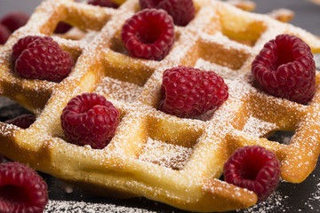 fresh waffles garnished with powdered sugar and raspberries