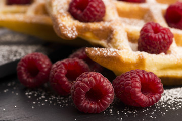 fresh waffles garnished with powdered sugar and raspberries