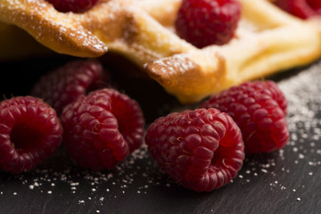 fresh waffles garnished with powdered sugar and raspberries