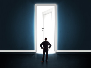Business man looking at big bright opened door