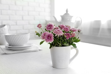 Beautiful flowers in decorative vase on table, on light background