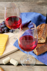Still life of wine, grape, cheese and bread on rustic wooden background