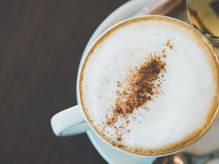 Vintage tone of cup of hot capuchino coffee on the brown table