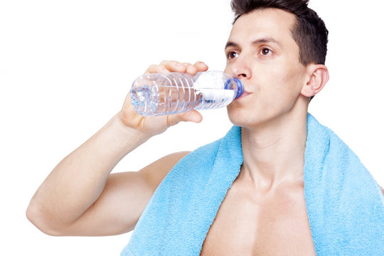 Close-up of a fit man drinking a bottle of water, isolated on wh