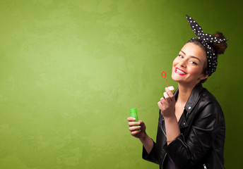 Obraz premium Beautiful woman blowing soap bubble on copyspace background