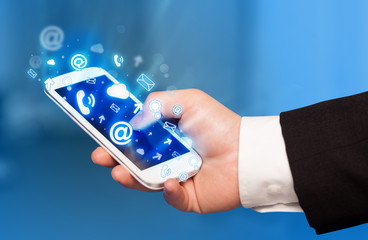 Business man holding smart phone with media icons