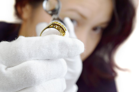 ルーペを除いて指輪を鑑定する女性