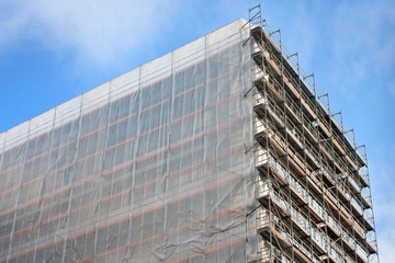 Staircase and scaffolding on a construction site,covered with mesh on sky background 