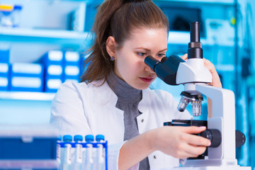 Female scientist looking through a microscope in laboratory