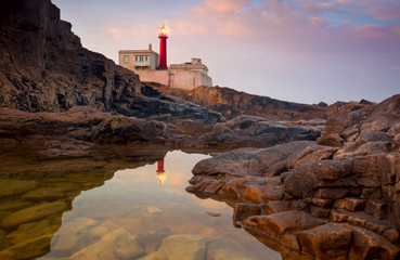 Lighthouse at beautiful sunrise sky and its reflection is in