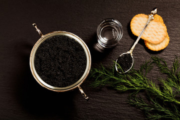 Obraz na płótnie Canvas Black caviar served on crackers with vodka and additives