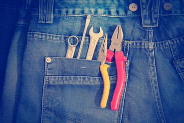 Several tools on a denim workers pocket.