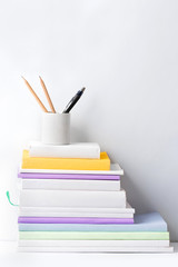stack of books and stationery in glass on white background