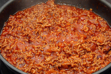 preparation sauce bolognese: mincemeat, onion and garlic in frying-pan on stove
