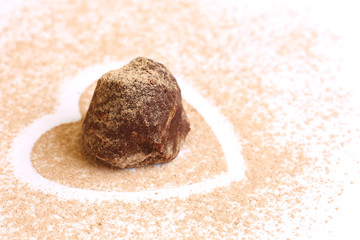 Fototapeta na wymiar isolated chocolate truffle on сocoa powder heart shape with copy space 