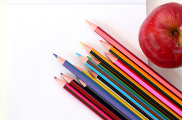Naklejka premium school supplies: blank notebook, pencils, pens and ripe red apple 