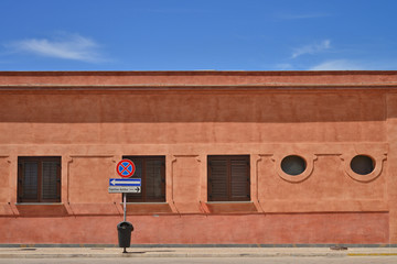 facciata di palazzo colore mattone, cartello di  capolinea autobus
