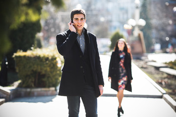 businessman talking on the phone while woman comes to him