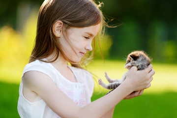 Adorable little girl playing with small kitten © MNStudio
