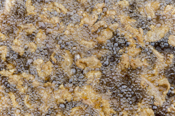 crackling / pork skin deep frying in oil in a cast iron frying