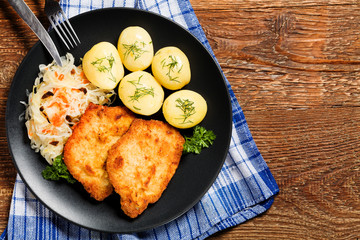 Fried pork chop in breadcrumbs, served with boiled potatoes and