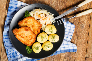 Fried pork chop in breadcrumbs, served with boiled potatoes and