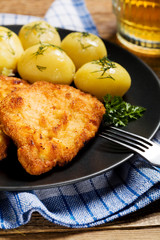 Fried pork chop in breadcrumbs, served with boiled potatoes and
