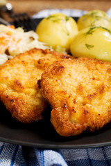 Fried pork chop in breadcrumbs, served with boiled potatoes and