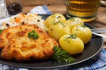 Fried pork chop in breadcrumbs, served with boiled potatoes and