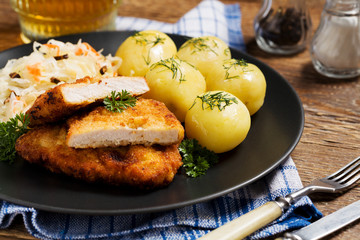 Fried pork chop in breadcrumbs, served with boiled potatoes and