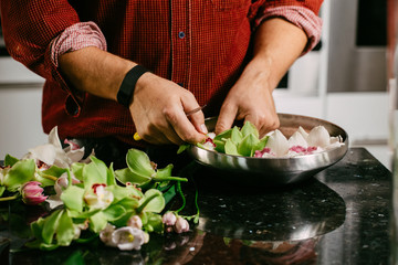 Man making flowers arrangment with green and white orhids
