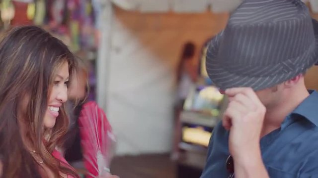 A couple trying things on while shopping at a fair
