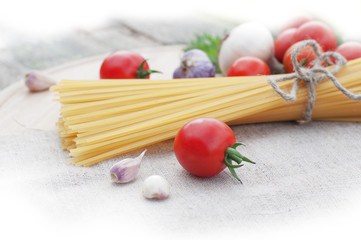 Pasta spaghetti, onion, garlic and tomato on wooden background