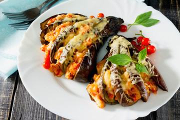 Baked eggplant with cheese, tomatoes and chicken on a dark woode